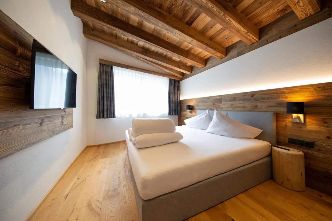 Double bedroom with timber wall panels and exposed ceiling beams at A CASA Brilliant in Sölden, Austria.