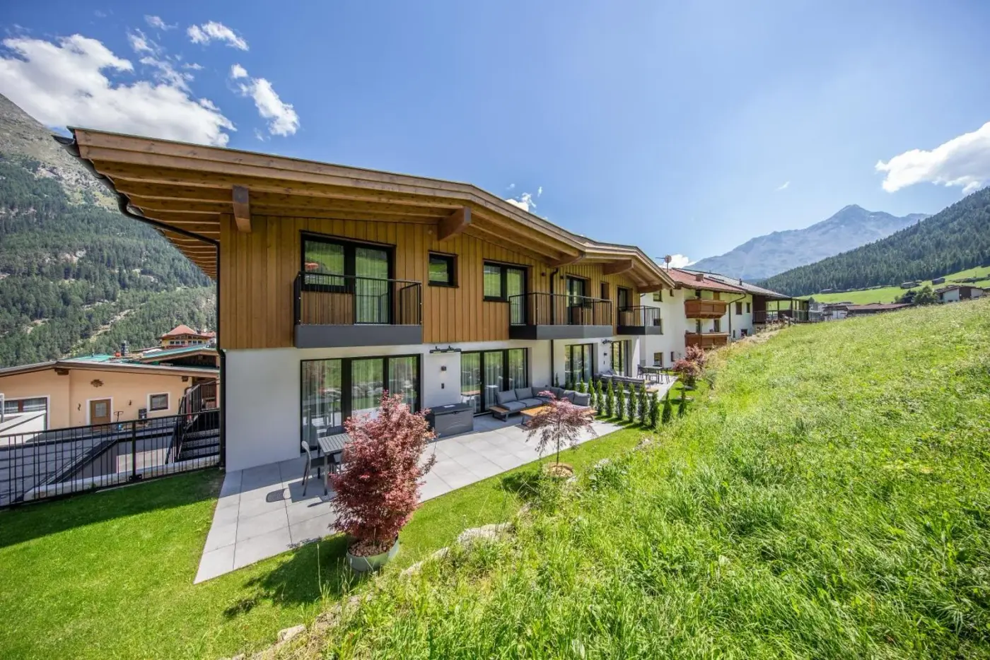 Timber chalet exterior beside a green alpine meadow at A CASA Brilliant in Sölden, Austria.