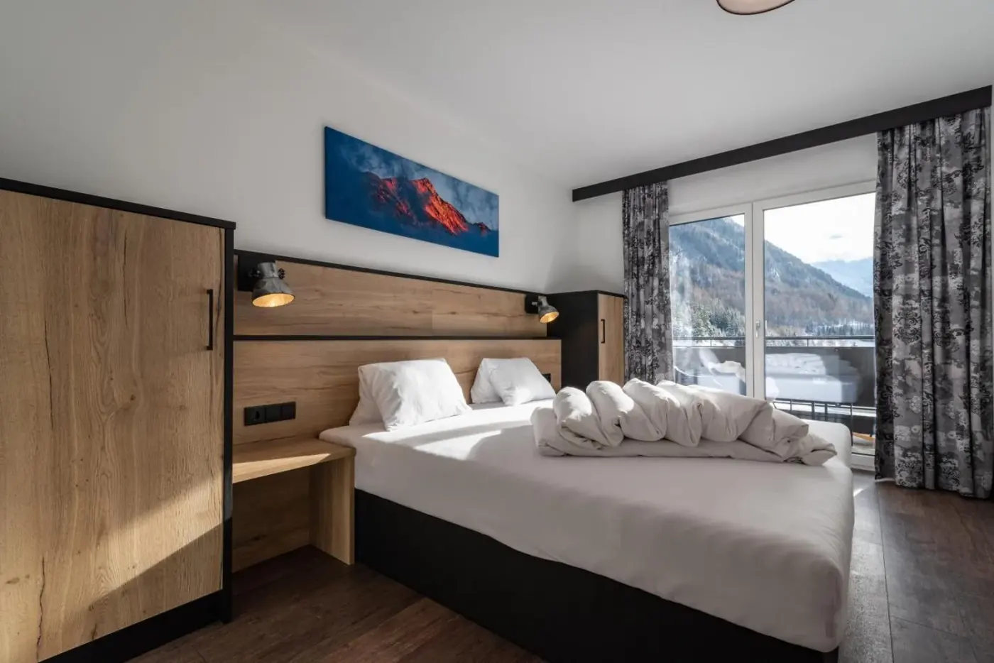 Double bedroom with a timber headboard and mountain-facing balcony doors at A CASA Rubin Chalet in Sölden, Austria.