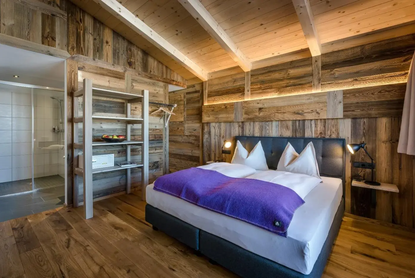 Double bedroom with exposed timber beams and a glass partition at almlust in Flachau, Austria.