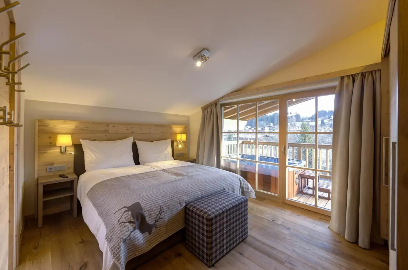 Double bedroom with timber furniture and large balcony doors at Alpen Chalet Dorfwies in Kirchberg in Tirol, Austria.