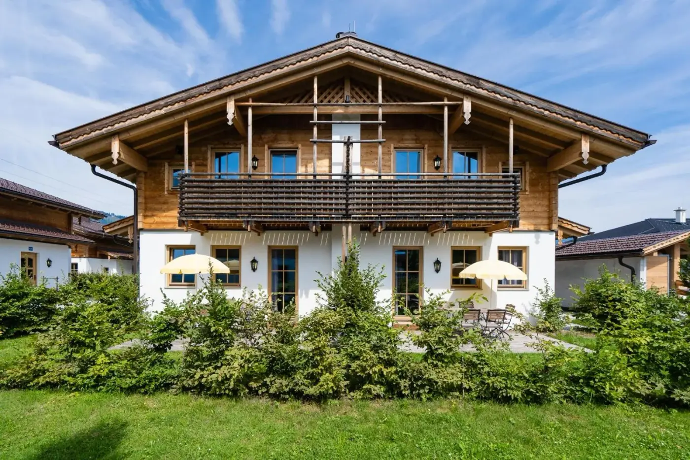 Timber chalet exterior with balconies and a garden at Alpenchalets Flachauer Gutshof in Flachau, Austria.