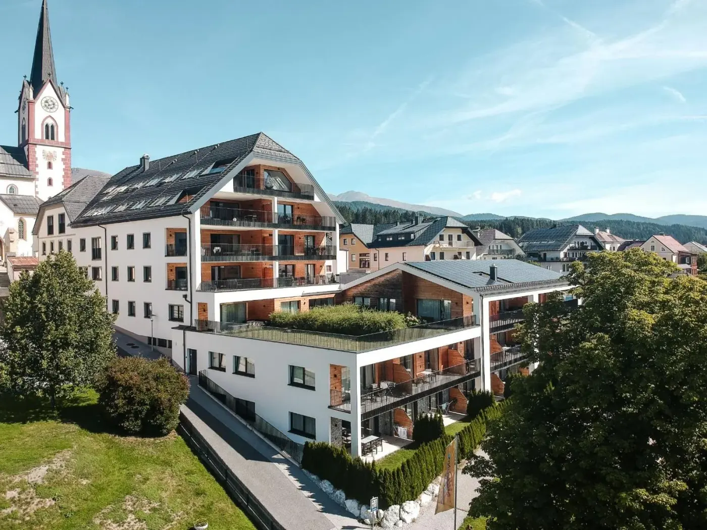 Alpine apartment building exterior beside the village church at AlpenParks Carpe Solem Mariapfarr in Mariapfarr, Austria.