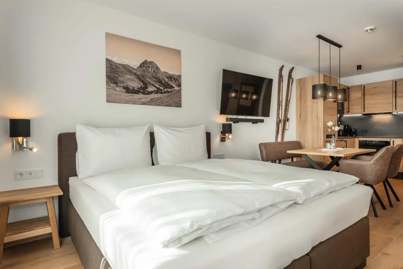 Double bedroom with a timber feature wall and adjoining kitchen area at AlpenParks Hotel and Apartment Taxacher in Kirchberg in Tirol, Austria.