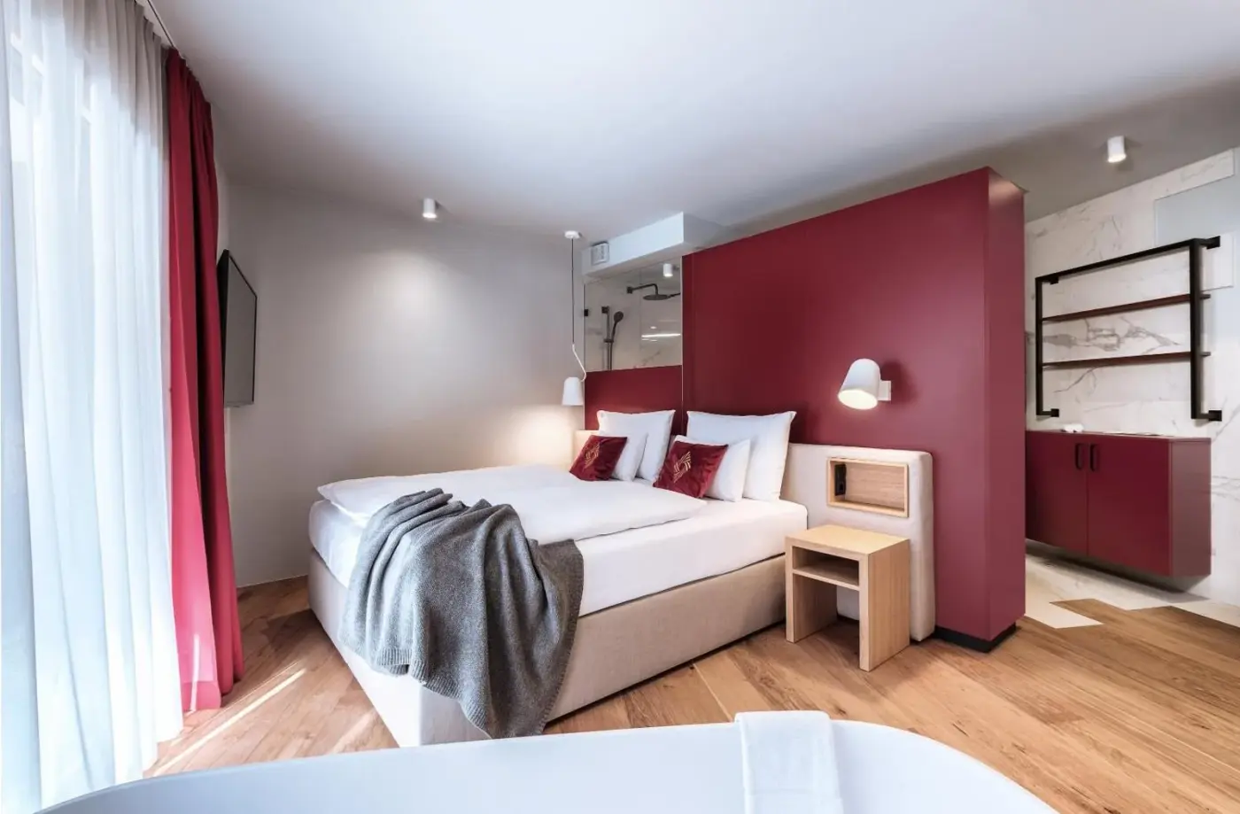Double bedroom with a red feature wall and large windows at AlpenParks The Secret Sölden in Sölden, Austria.