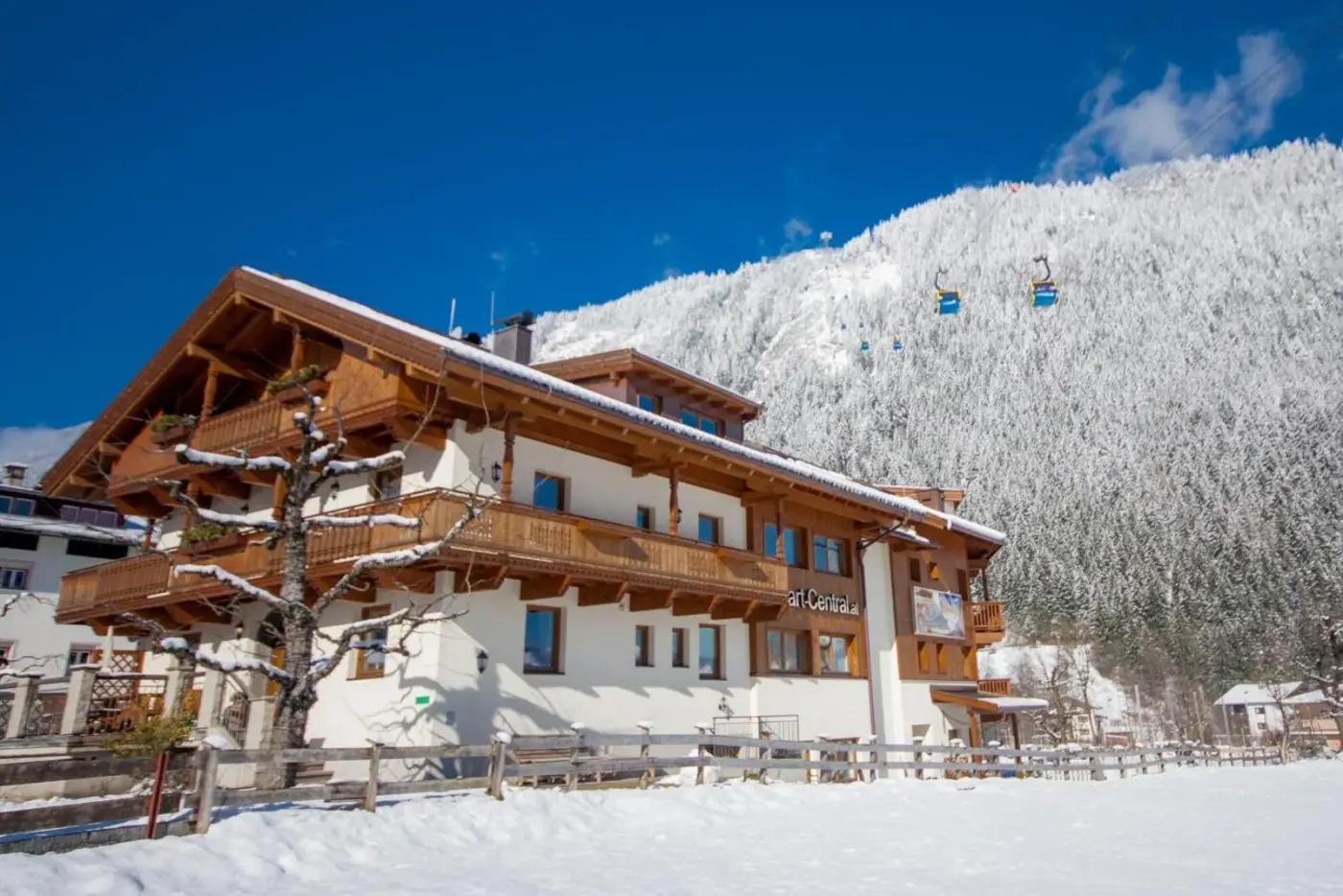 Alpine apartment lodge with timber balconies beneath snowy mountains at Apart Central in Mayrhofen, Austria.