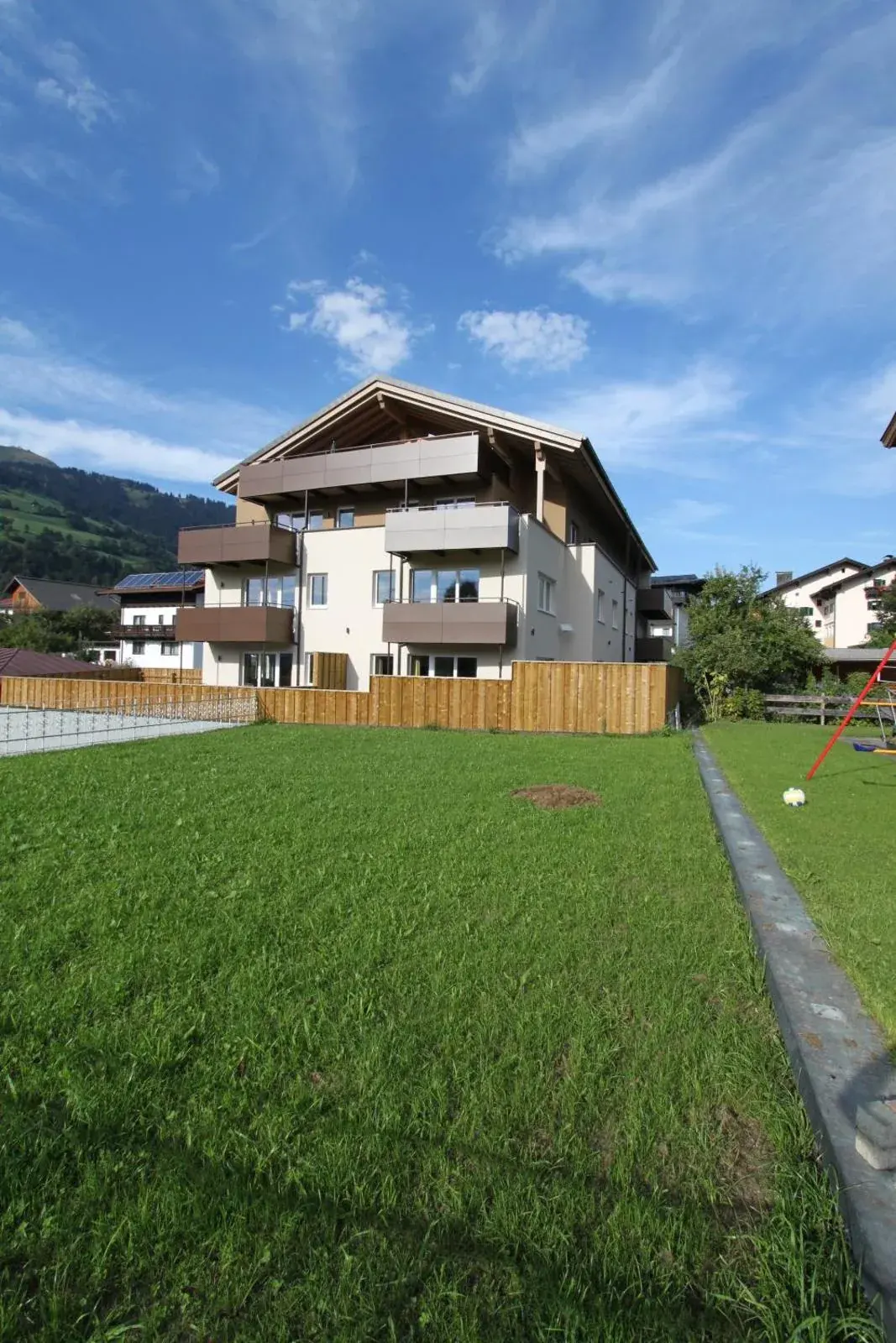 Alpine apartment building beside a green meadow at Apart Resort Rabl in Westendorf, Austria.