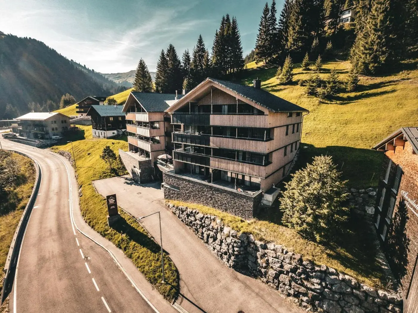 Aparthotel exterior with balconies on a green alpine hillside at Aparthotel Alpinresort Damüls in Damüls, Austria.