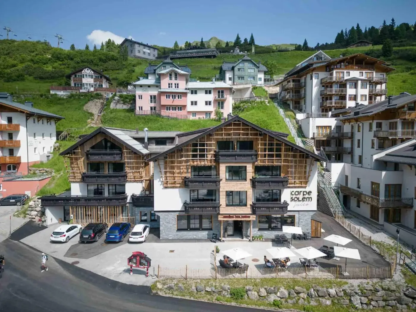 Alpine aparthotel exterior beneath green hills at CARPE SOLEM Jules in Obertauern, Austria.