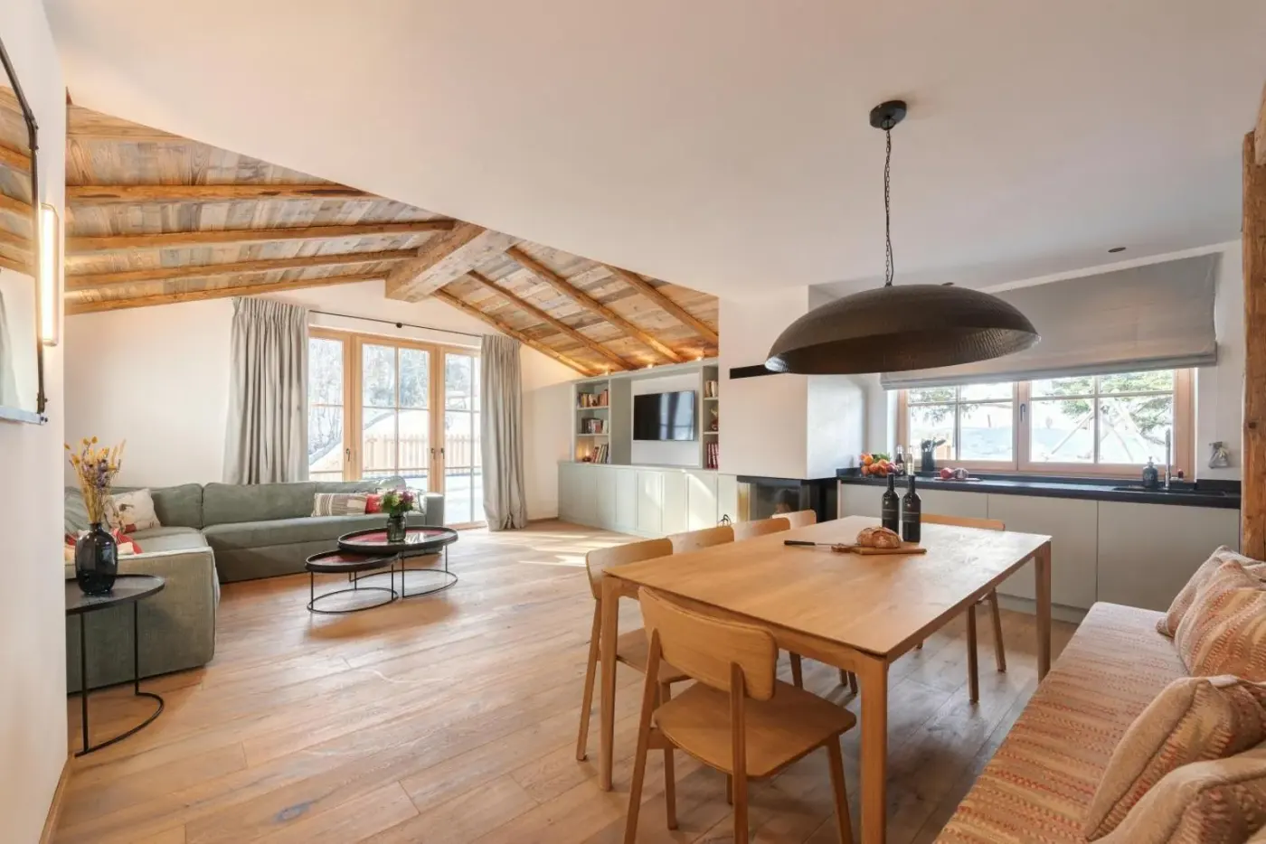 Open-plan living and dining area with sofas and a wooden table at Chalet Marmotta CULM in Sankt Anton am Arlberg, Austria.