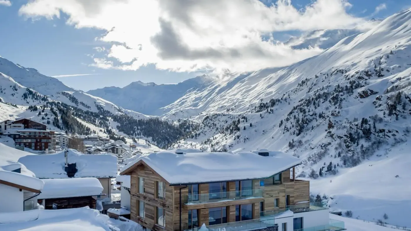 Alpine chalet apartment building beneath snow-covered mountains at Chalet Obergurgl Luxury Apartments in Obergurgl, Austria.