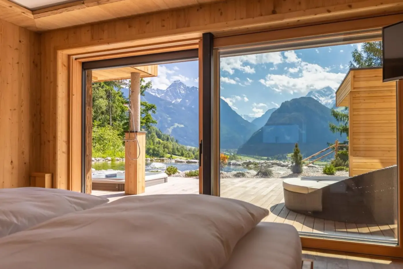 Double bedroom with glazed doors facing a mountain-view terrace at Chalet Residenz Zillertal Mühlermoos in Ramsau im Zillertal, Austria.