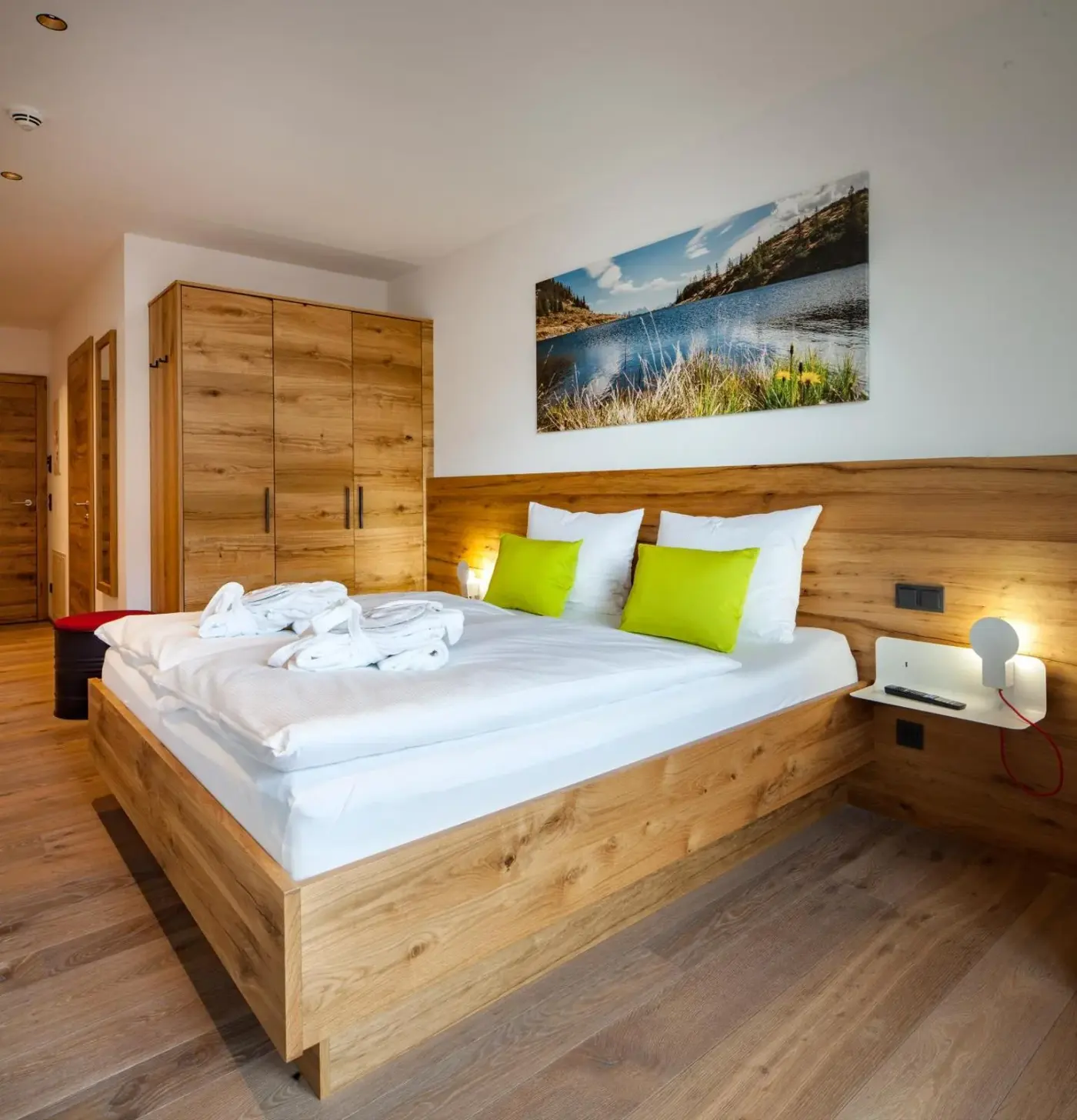 Double bedroom with timber furniture and green accent cushions at Das Heimsitz in Brixen im Thale, Austria.