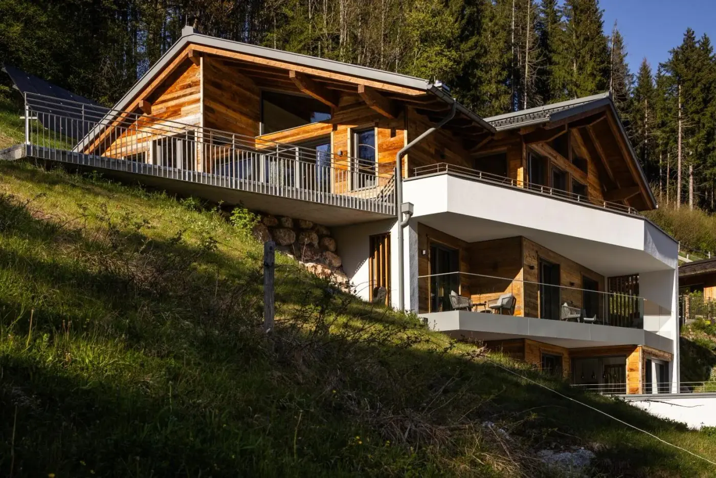 Modern timber chalet exterior on a wooded hillside at DasKöniglich Luxury Alpine Chalet in Mühlbach am Hochkönig, Austria.