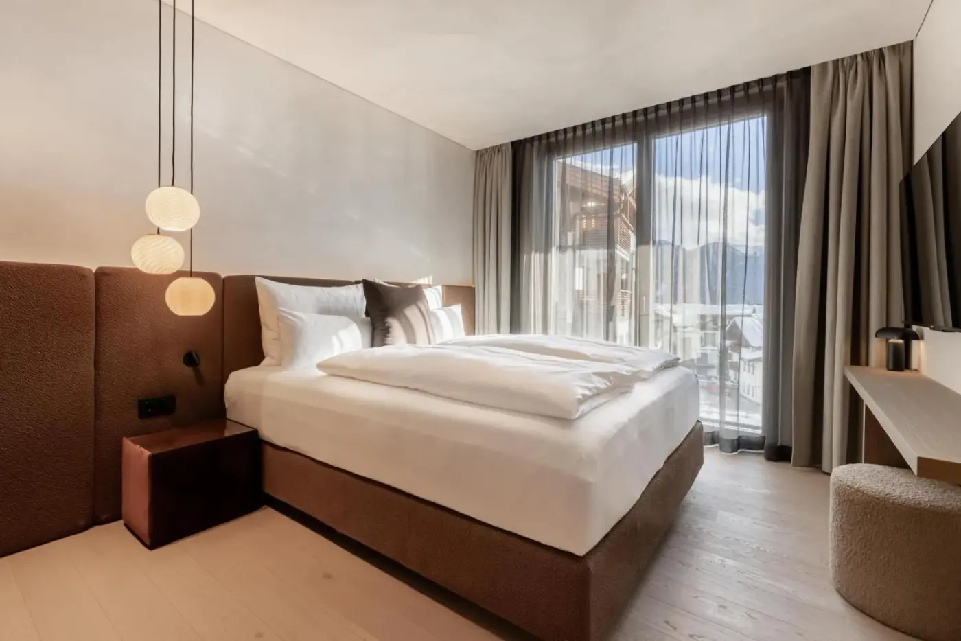 Double bedroom with pendant lights and glazed balcony doors at Domenigs Luxury Apartments in Fiss, Austria.