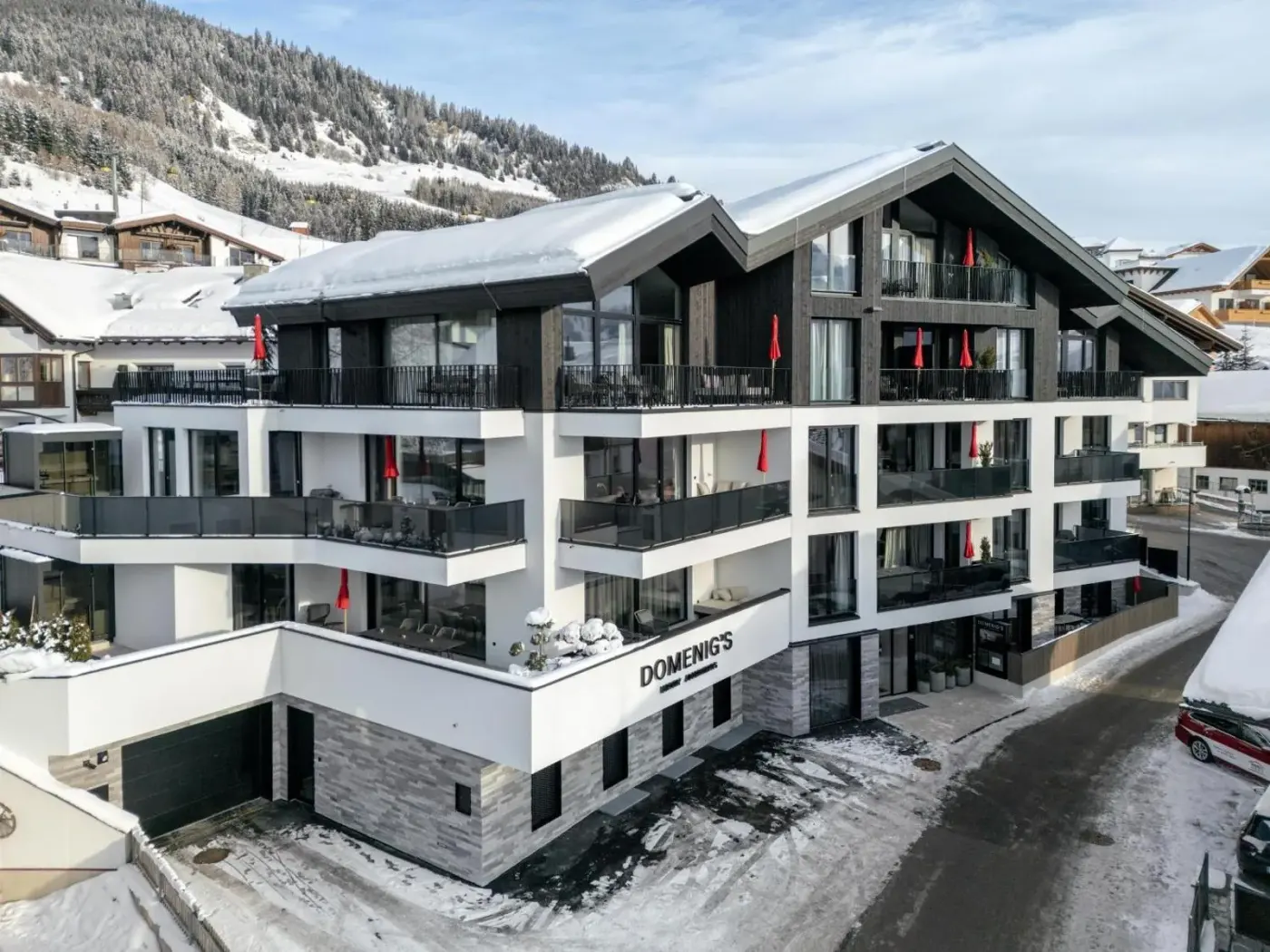 Modern apartment building with balconies and snow-covered pitched roofs at Domenigs Luxury Apartments in Fiss, Austria.