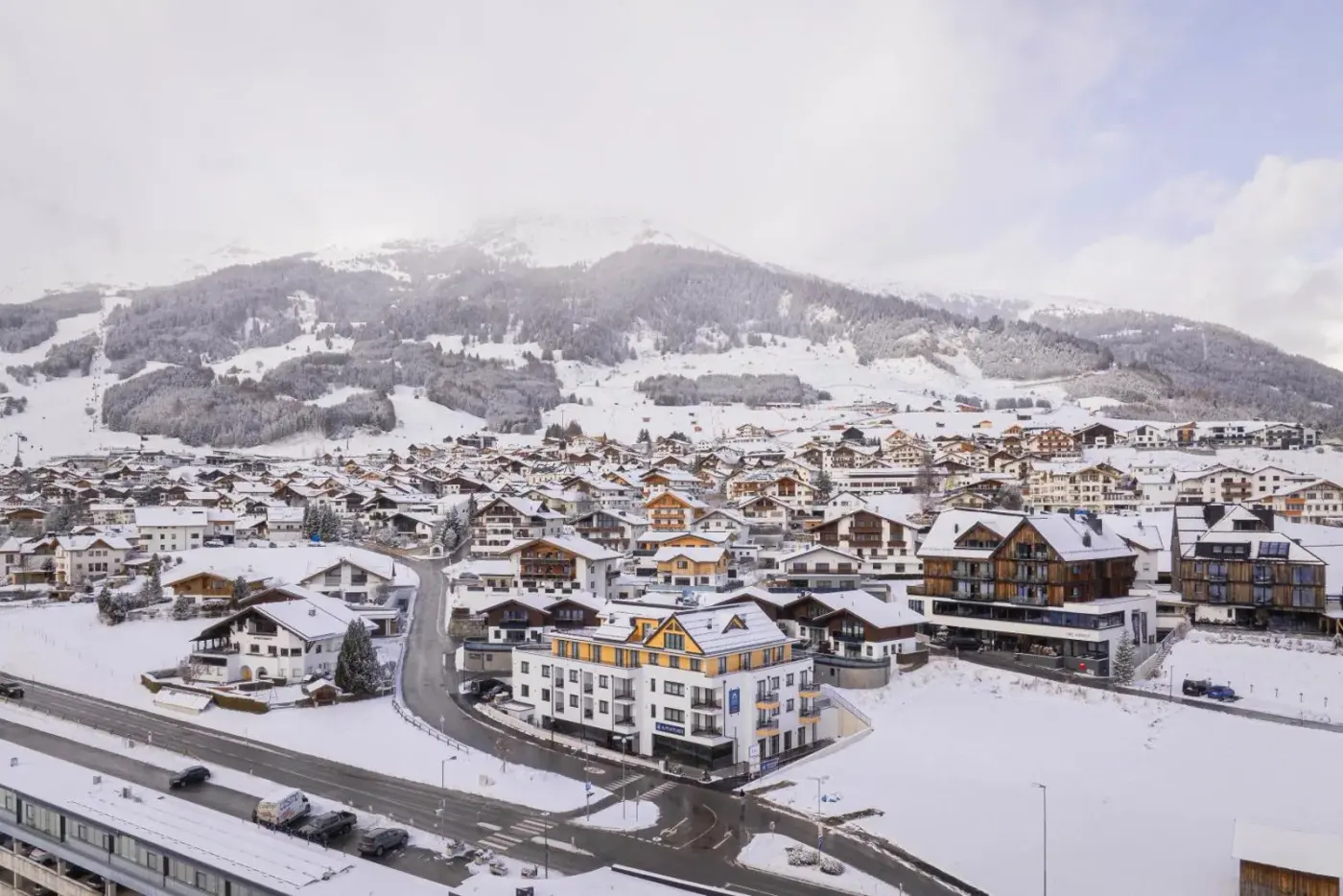 Aerial view of the apartment resort amid a snow-covered Alpine village at Fiss Suites by ALPS RESORTS in Fiss, Austria.
