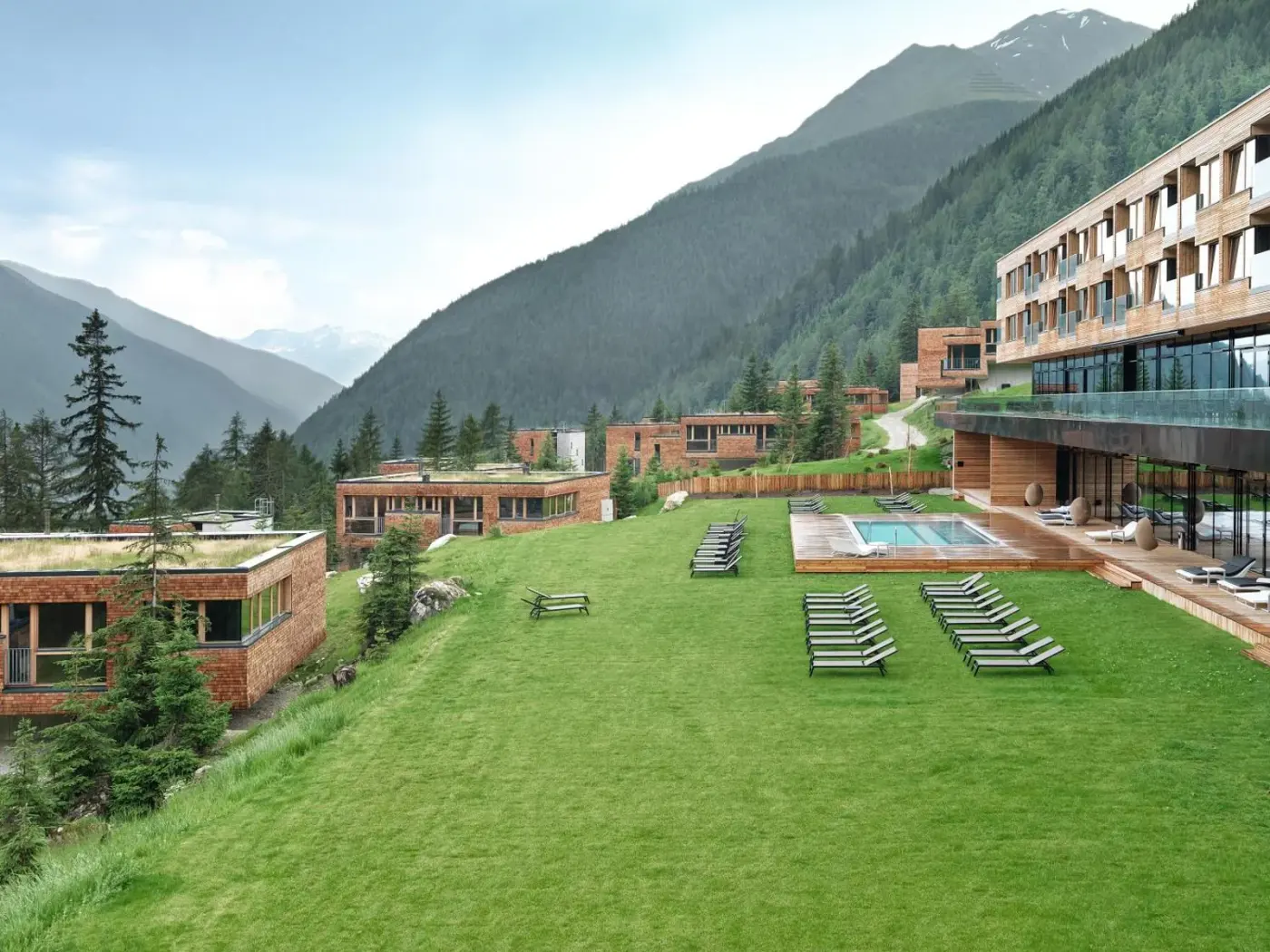 Resort garden with an outdoor pool, loungers and mountain views at Gradonna Mountain Resort Chalets and Hotel in Kals am Großglockner, Austria.