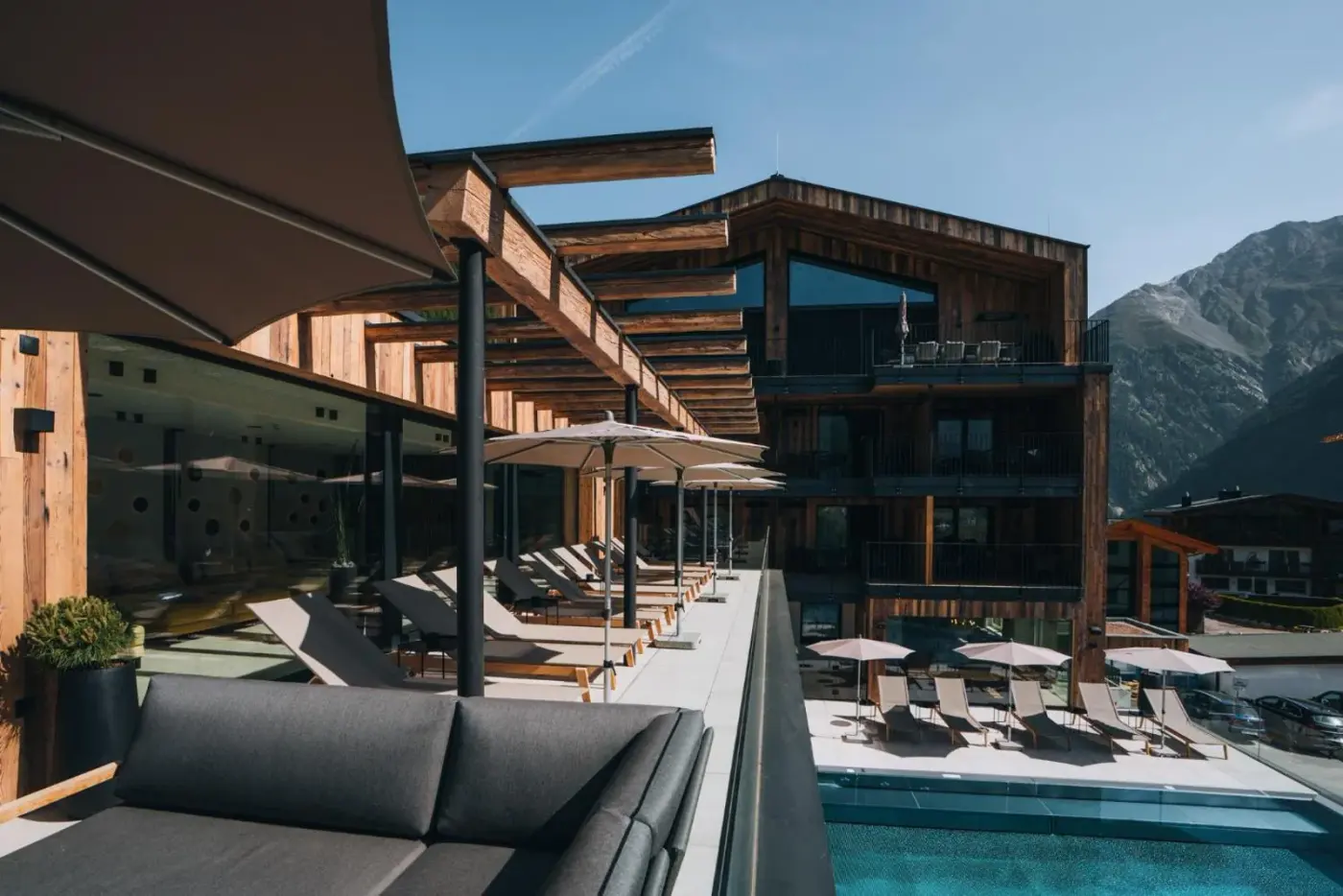 Modern alpine resort exterior with an outdoor pool and lounge terrace at Grünwald Resort Sölden in Sölden, Austria.