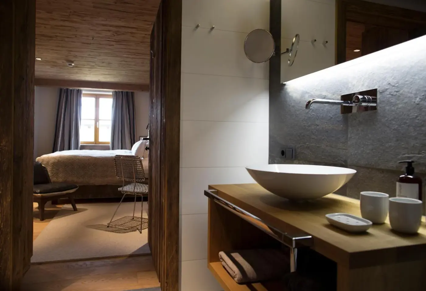 Bathroom vanity with a bowl basin and an adjoining bedroom at House Hannes Schneider Stuben in Stuben am Arlberg, Austria.