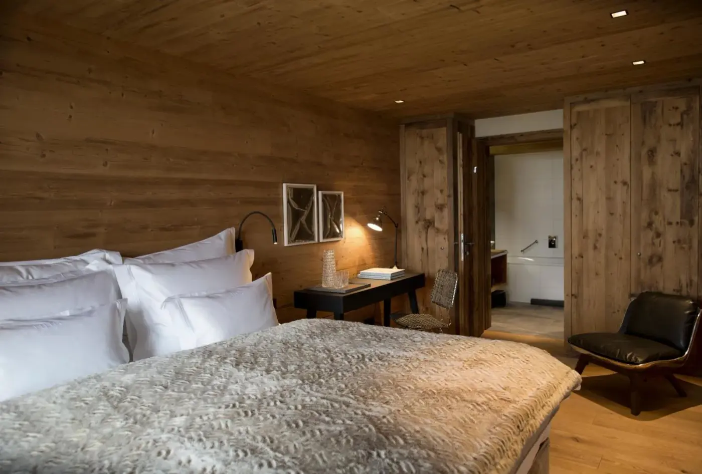 Double bedroom with timber walls and a cushioned bench at House Hannes Schneider Stuben in Stuben am Arlberg, Austria.