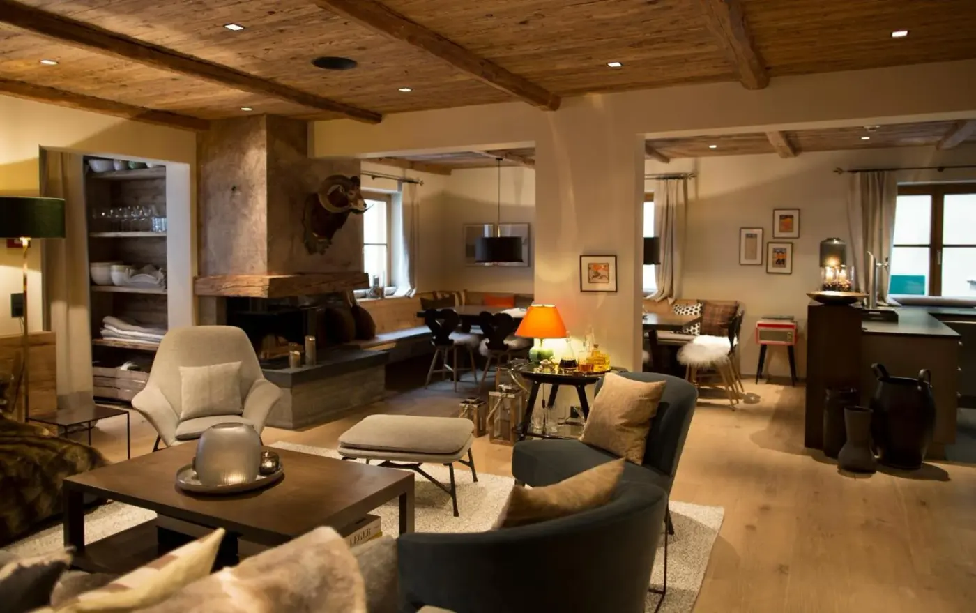 Lounge with armchairs, timber flooring and a stone fireplace at House Hannes Schneider Stuben in Stuben am Arlberg, Austria.