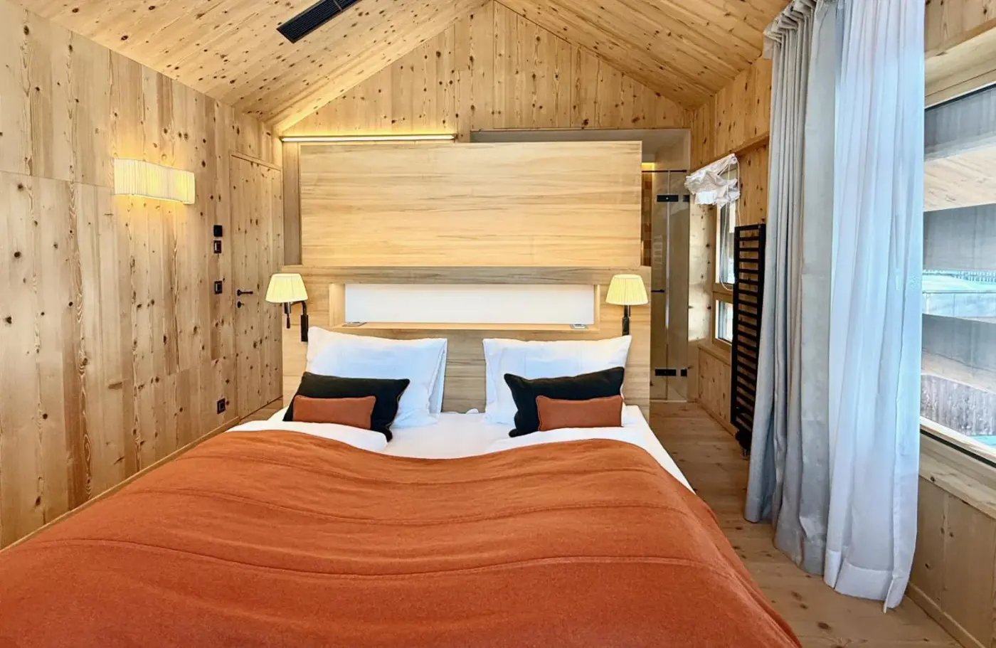 Double bedroom beneath a pitched timber roof with glazed terrace doors at Infinity Sky Lodge by belle-stay in Rohrberg, Austria.