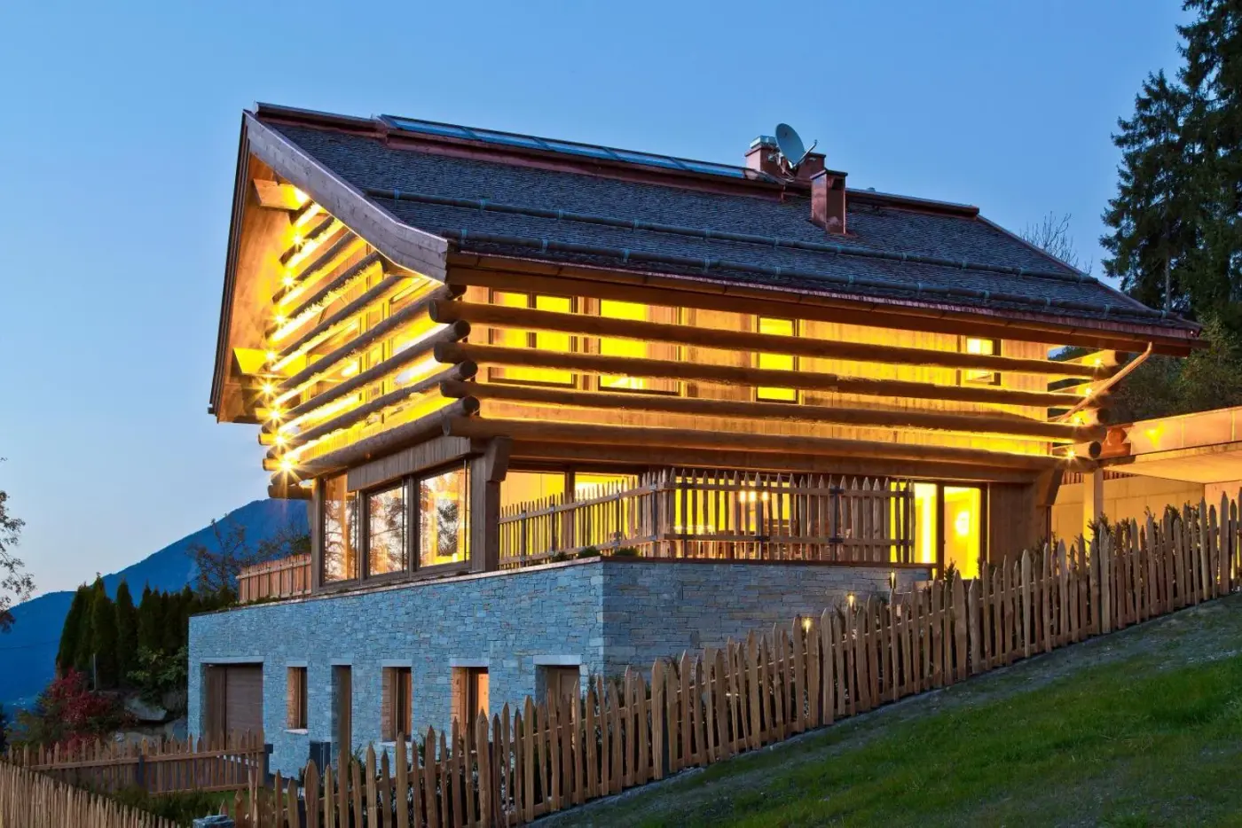 Illuminated timber lodge with broad windows at dusk at Infinity Sky Lodge by belle-stay in Rohrberg, Austria.