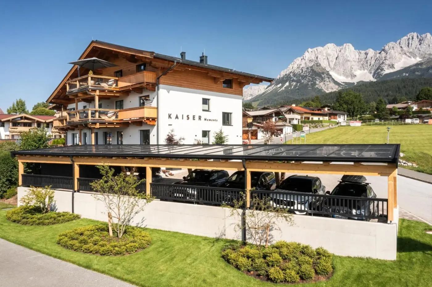 Alpine apartment building with timber balconies beneath rocky mountains at KaiserMoments in Going am Wilden Kaiser, Austria.