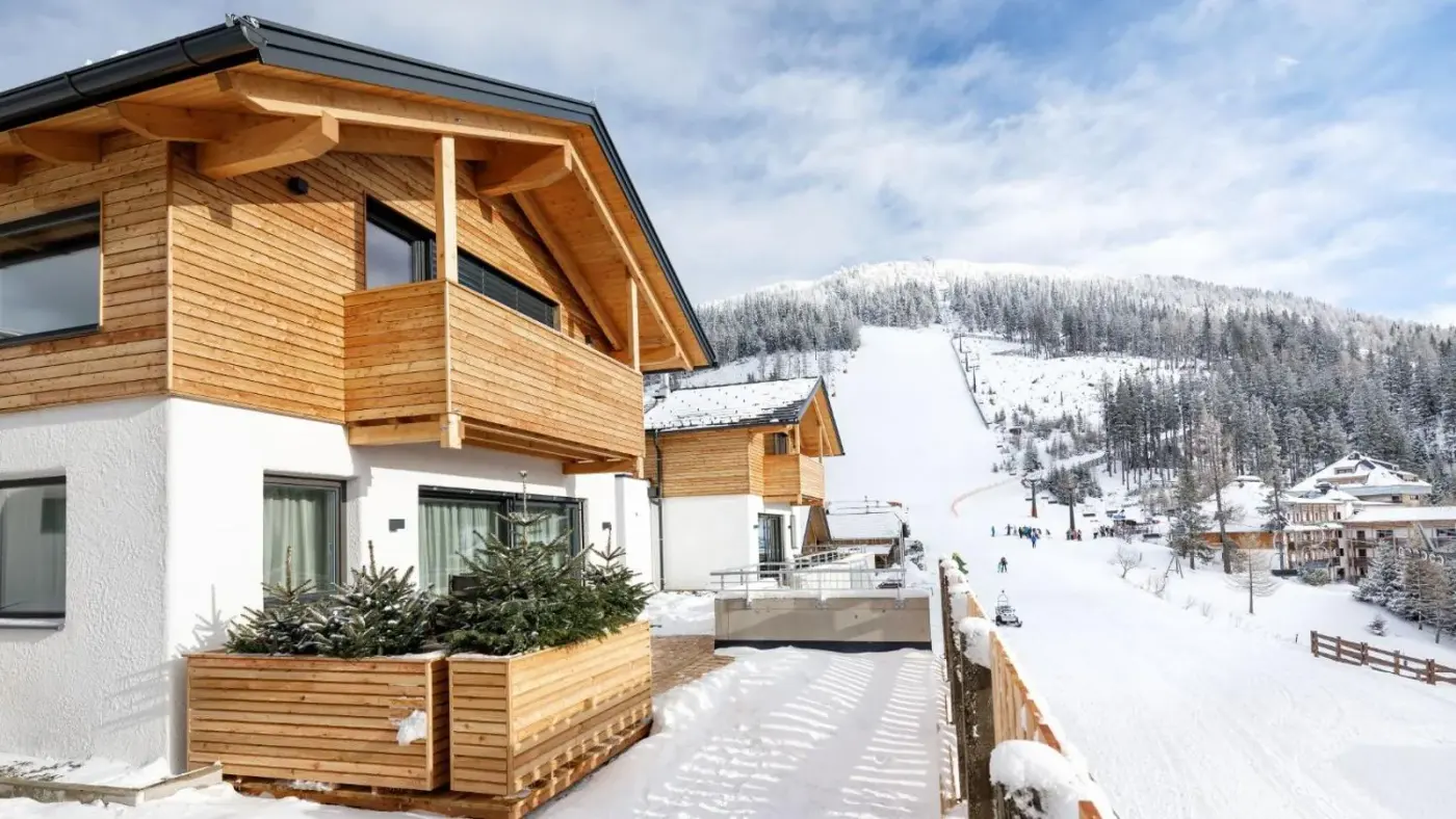 Timber lodge exterior beside snow-covered ski slopes at Katschberg Lodge in Katschberghöhe, Austria.