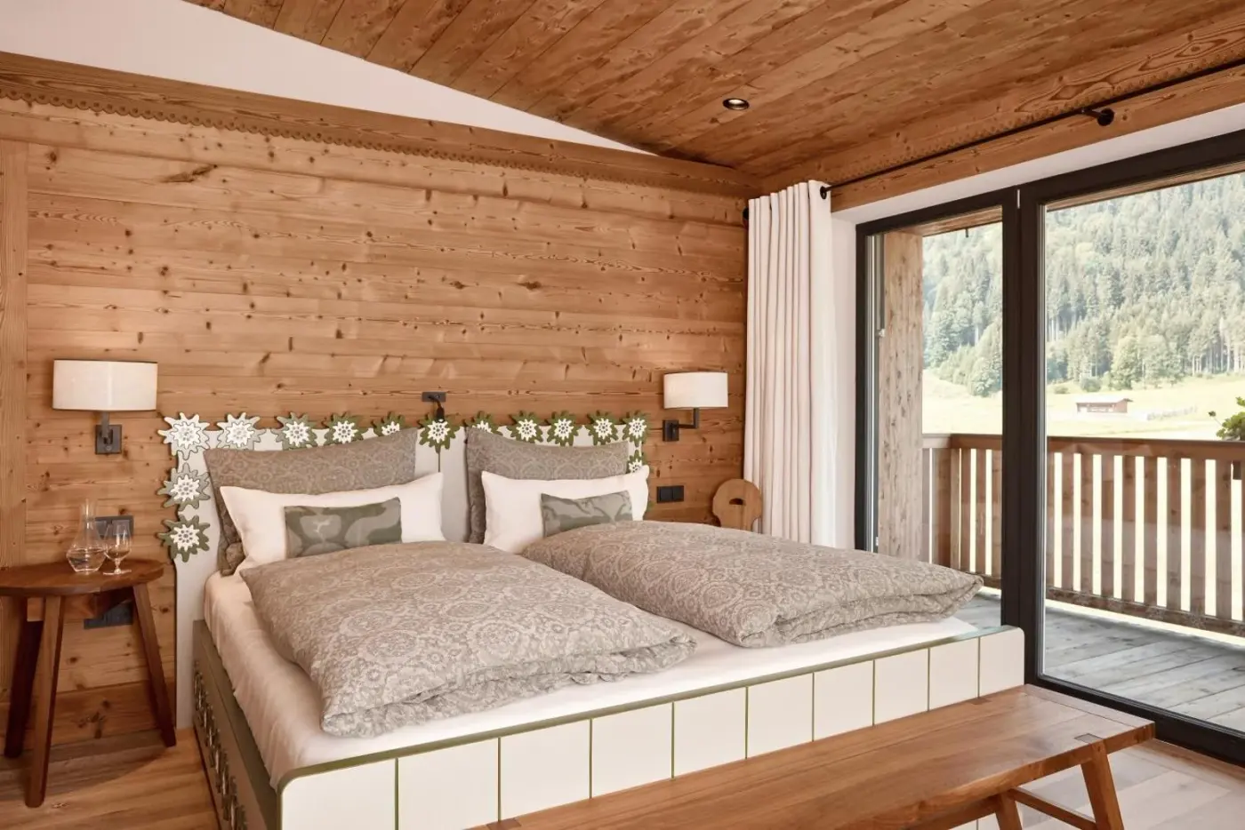 Double bedroom with timber walls and balcony doors at Kitzbühel Lodge in Reith bei Kitzbühel, Austria.