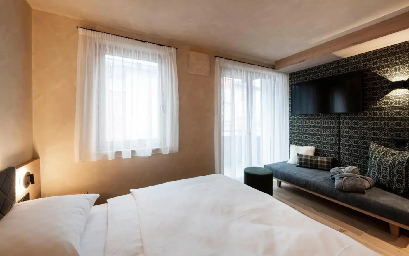 Double bedroom with a window seat and timber feature wall at LaMonte Luxury Apartments in Kitzbühel, Austria.