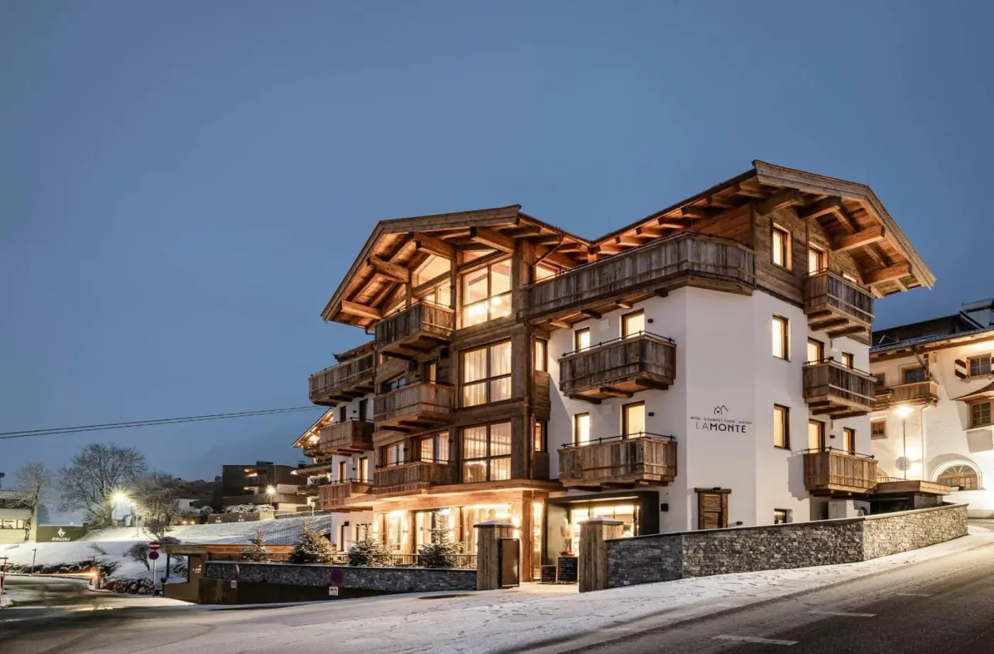 Illuminated alpine apartment building exterior at dusk at LaMonte Luxury Apartments in Kitzbühel, Austria.