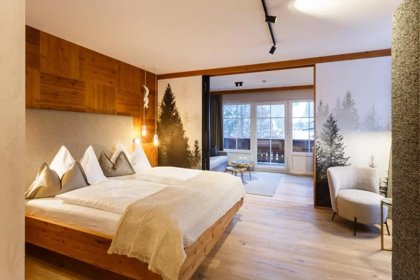 Double bedroom with timber accents and a forest-pattern feature wall at Landhotel Schermer in Westendorf, Austria.