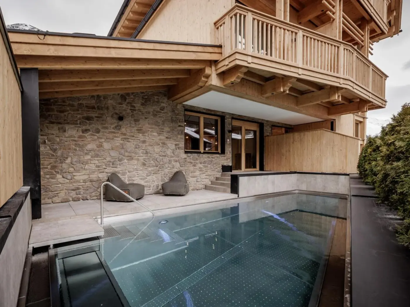 Timber lodge exterior beside an outdoor swimming pool at Leni Mountain Lodge in Sölden, Austria.