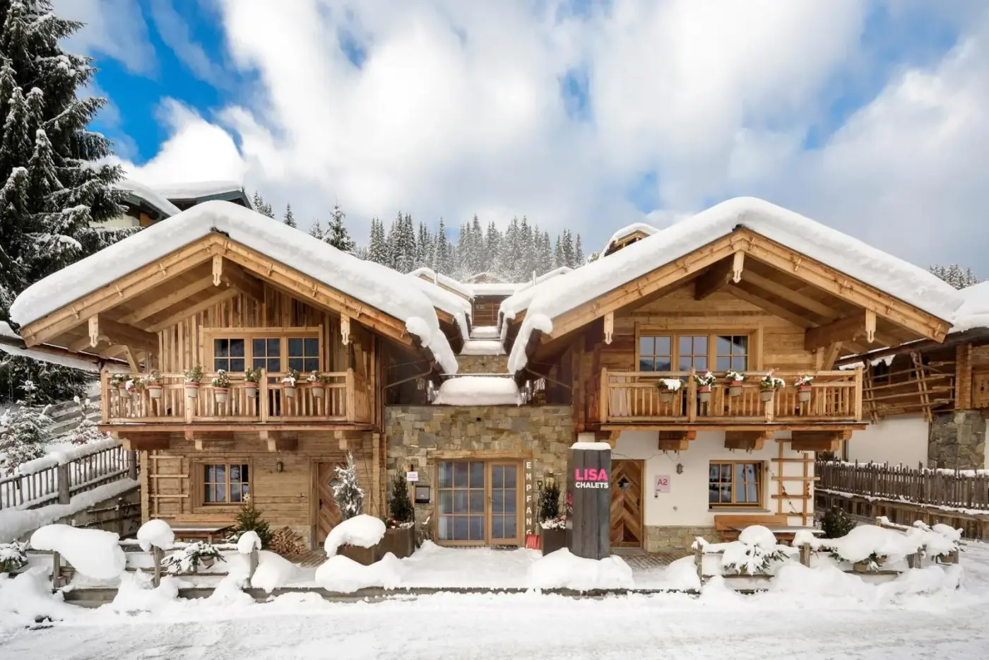Timber chalet exteriors with snow-covered roofs and balconies at LISA-Chalets in Flachau, Austria.