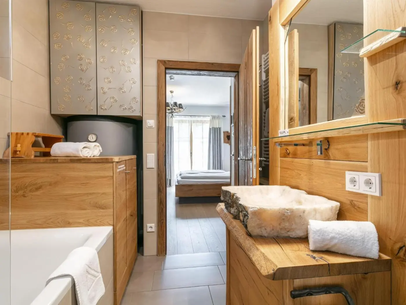 Bathroom with timber furniture, a vessel basin and bathtub at Maier Alm in Neukirchen am Großvenediger, Austria.