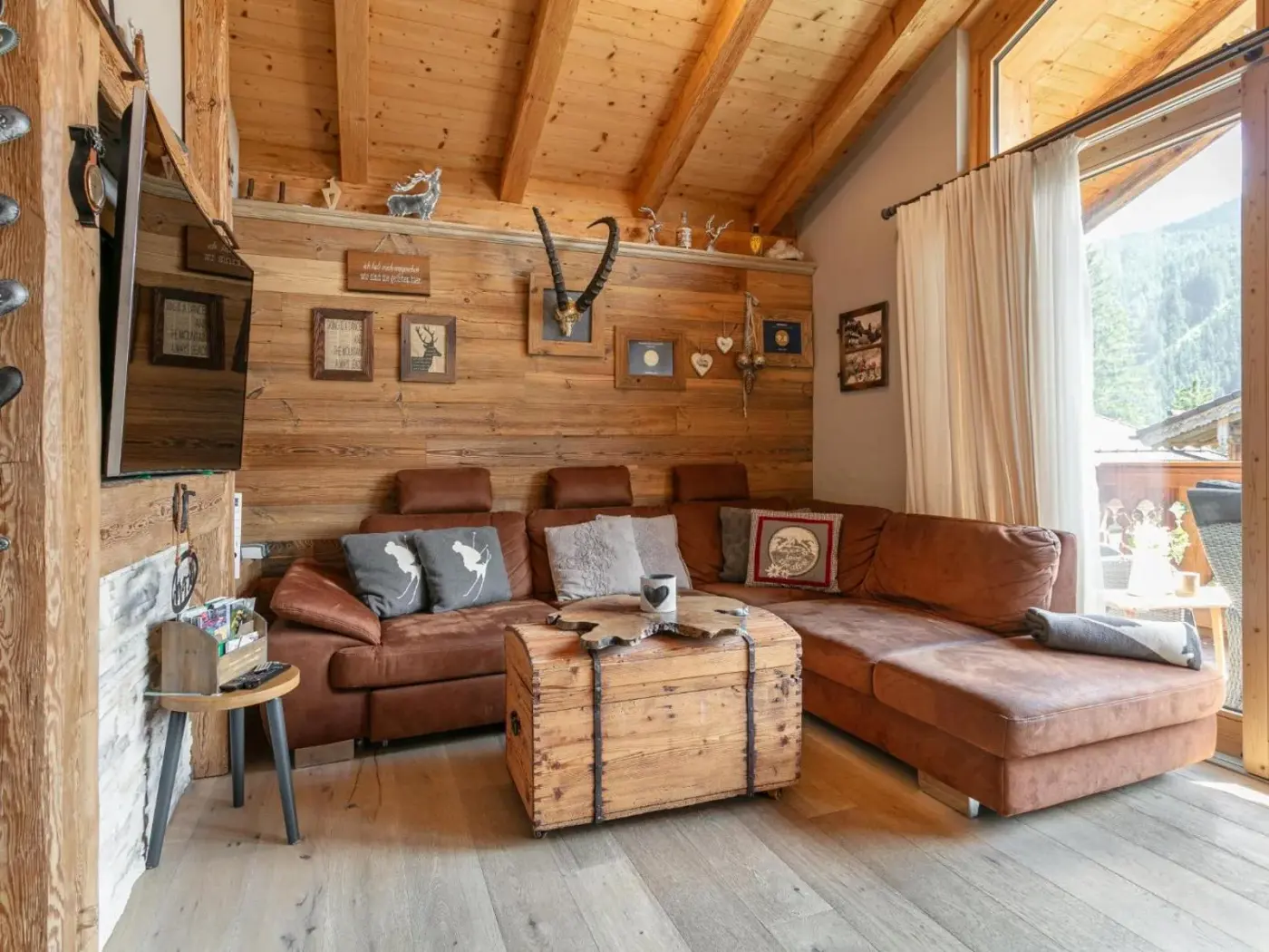 Living room with a corner sofa beneath a pitched timber roof at Maier Alm in Neukirchen am Großvenediger, Austria.