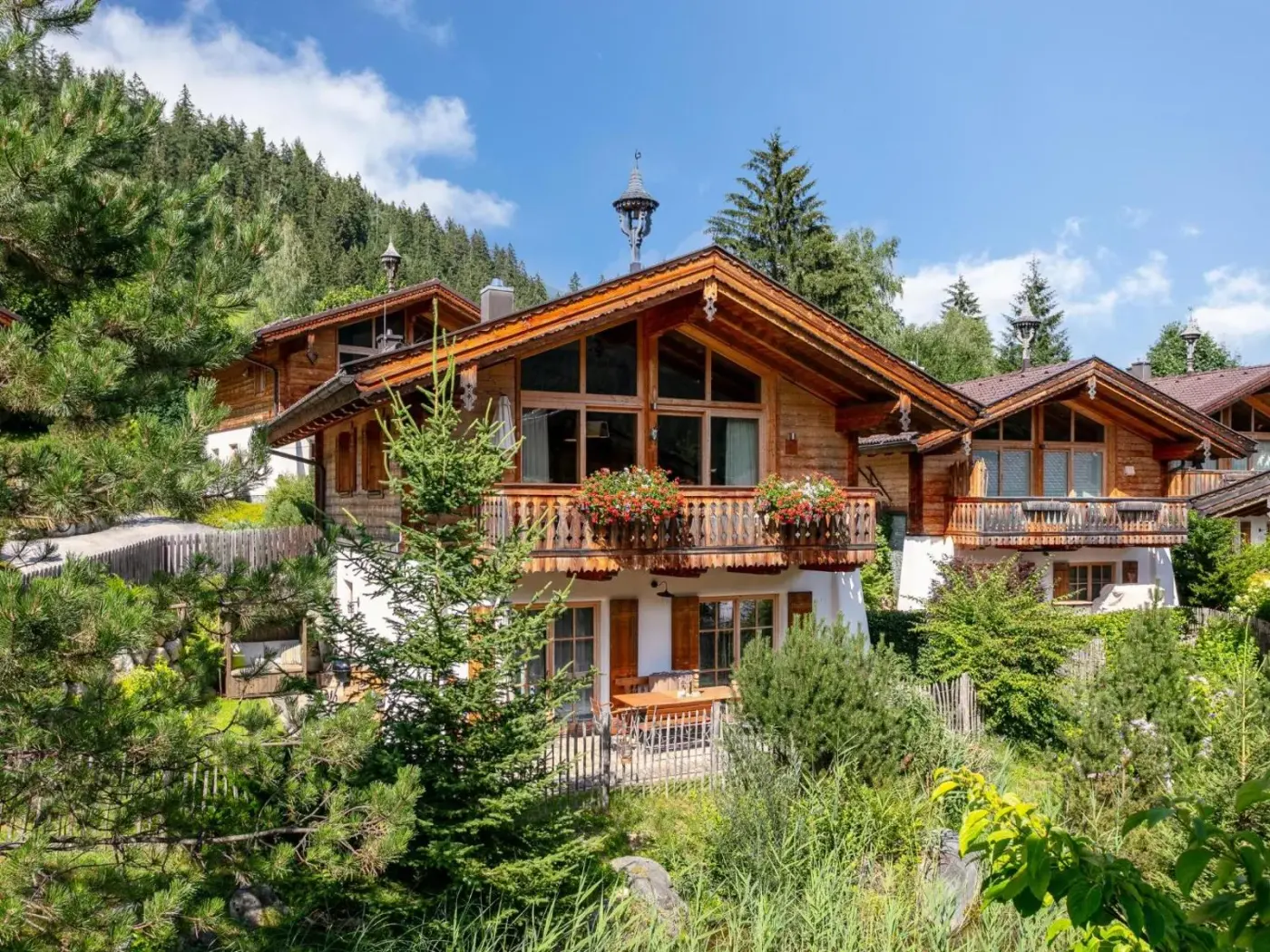 Timber chalet with flower-lined balconies beside a green garden at Maier Alm in Neukirchen am Großvenediger, Austria.