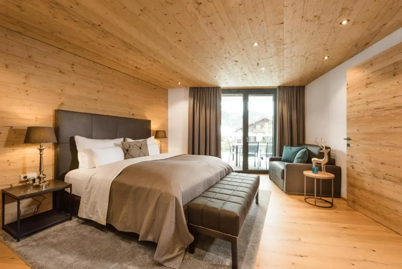 Double bedroom with a timber ceiling and balcony doors at Mountain Chalet Kirchberg in Kirchberg in Tirol, Austria.