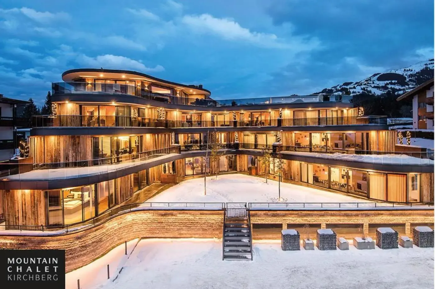 Illuminated modern alpine chalet building surrounded by snow at dusk at Mountain Chalet Kirchberg in Kirchberg in Tirol, Austria.