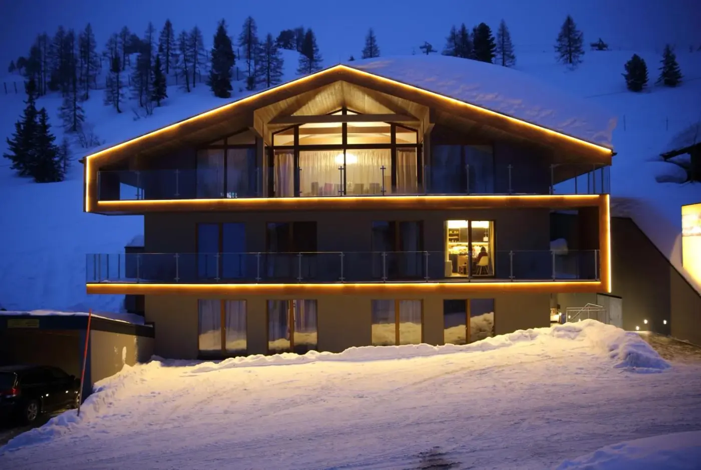 Illuminated modern alpine hotel exterior surrounded by snow at dusk at Mountain Vita in Obertauern, Austria.