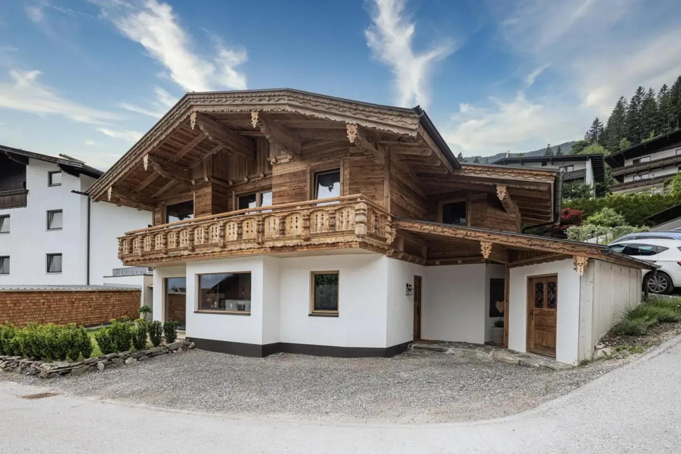 Alpine chalet with carved timber balconies beside a village road at Naturlodge Tirol in Fügen, Austria.
