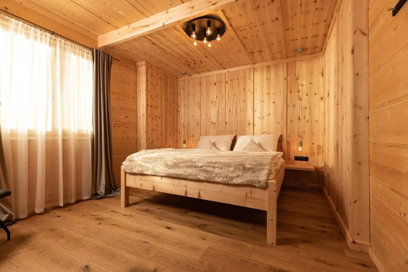 Double bedroom with timber walls and wooden flooring at Naturlodge Tirol in Fügen, Austria.
