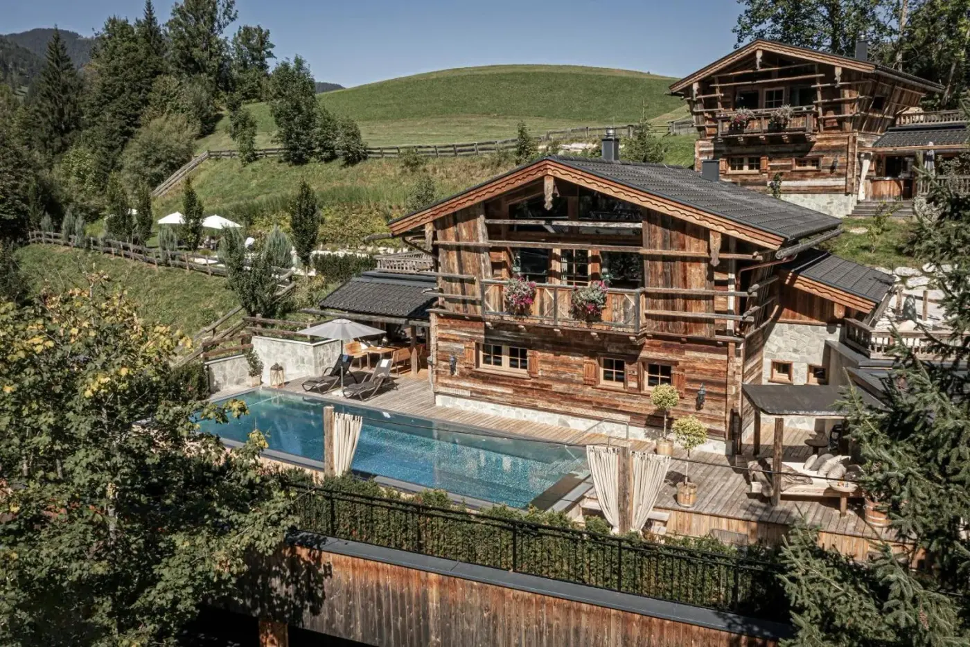 Rustic timber chalet exterior beside an outdoor swimming pool at Prechtlgut in Wagrain, Austria.