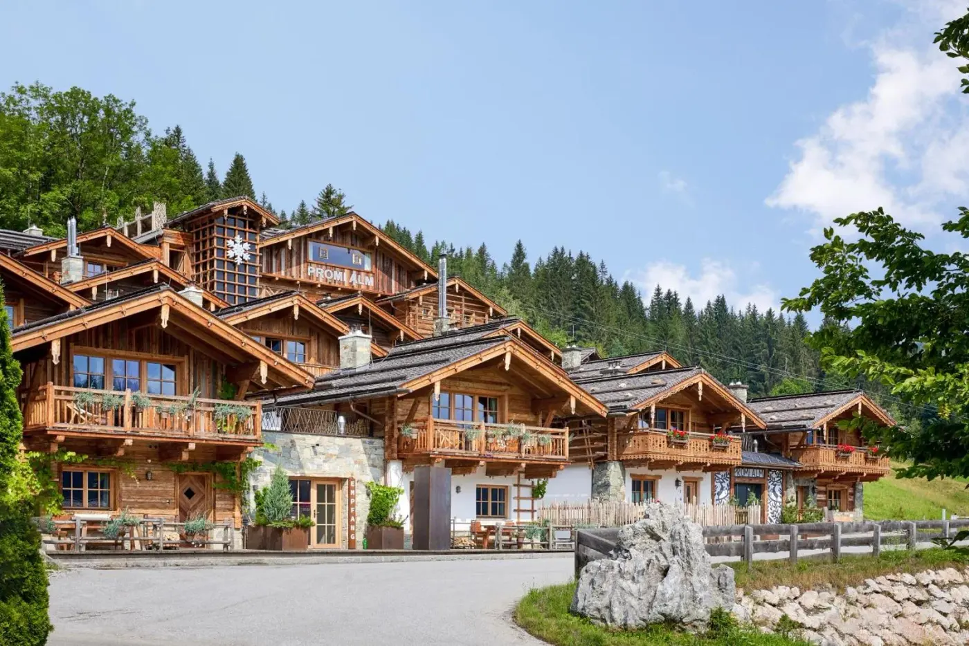 Timber chalet village with balconies and stone ground-floor walls at Promi Alm Flachau in Flachau, Austria.