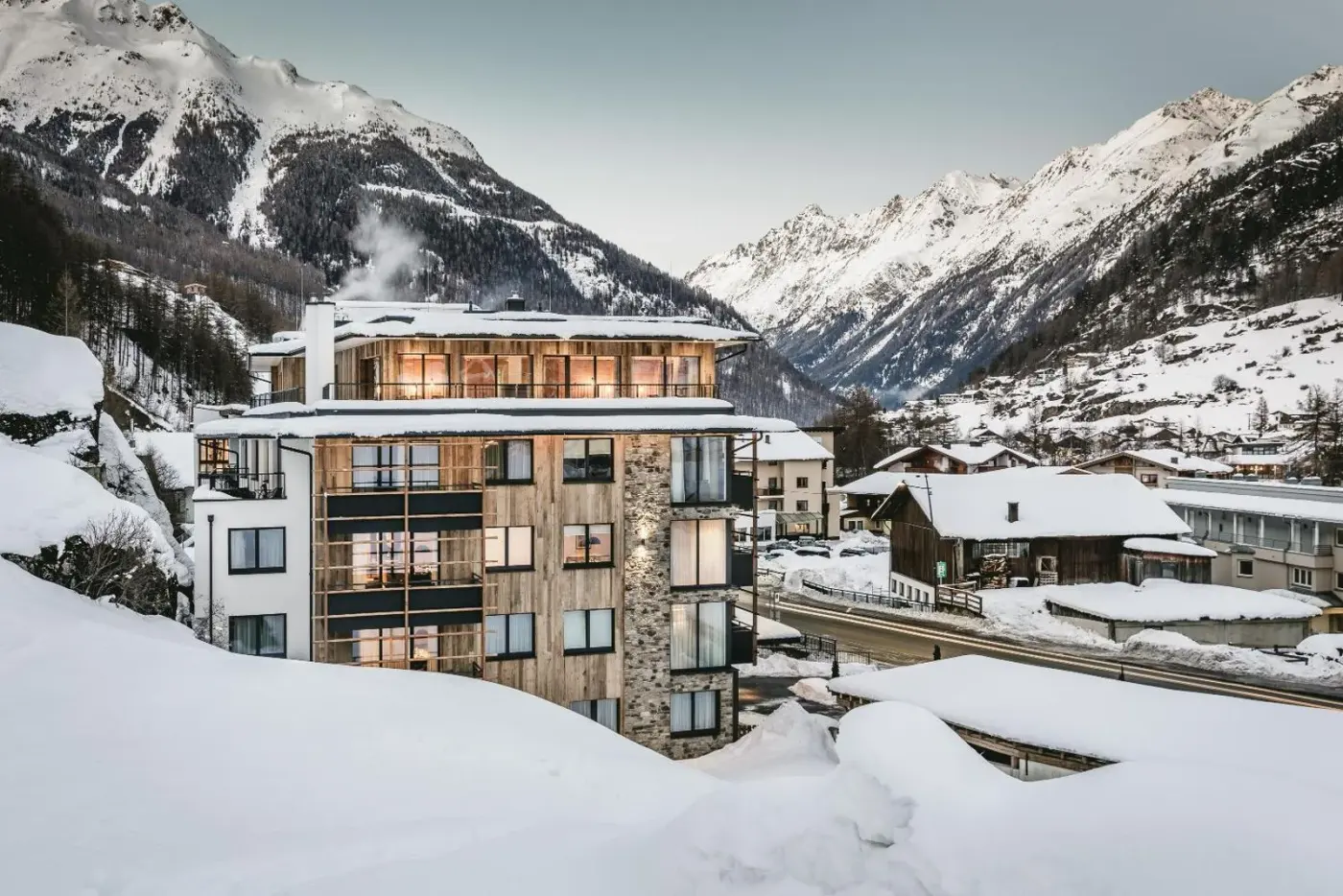 Alpine apartment building surrounded by snow-covered mountains at Valentin Design Apartments in Sölden, Austria.