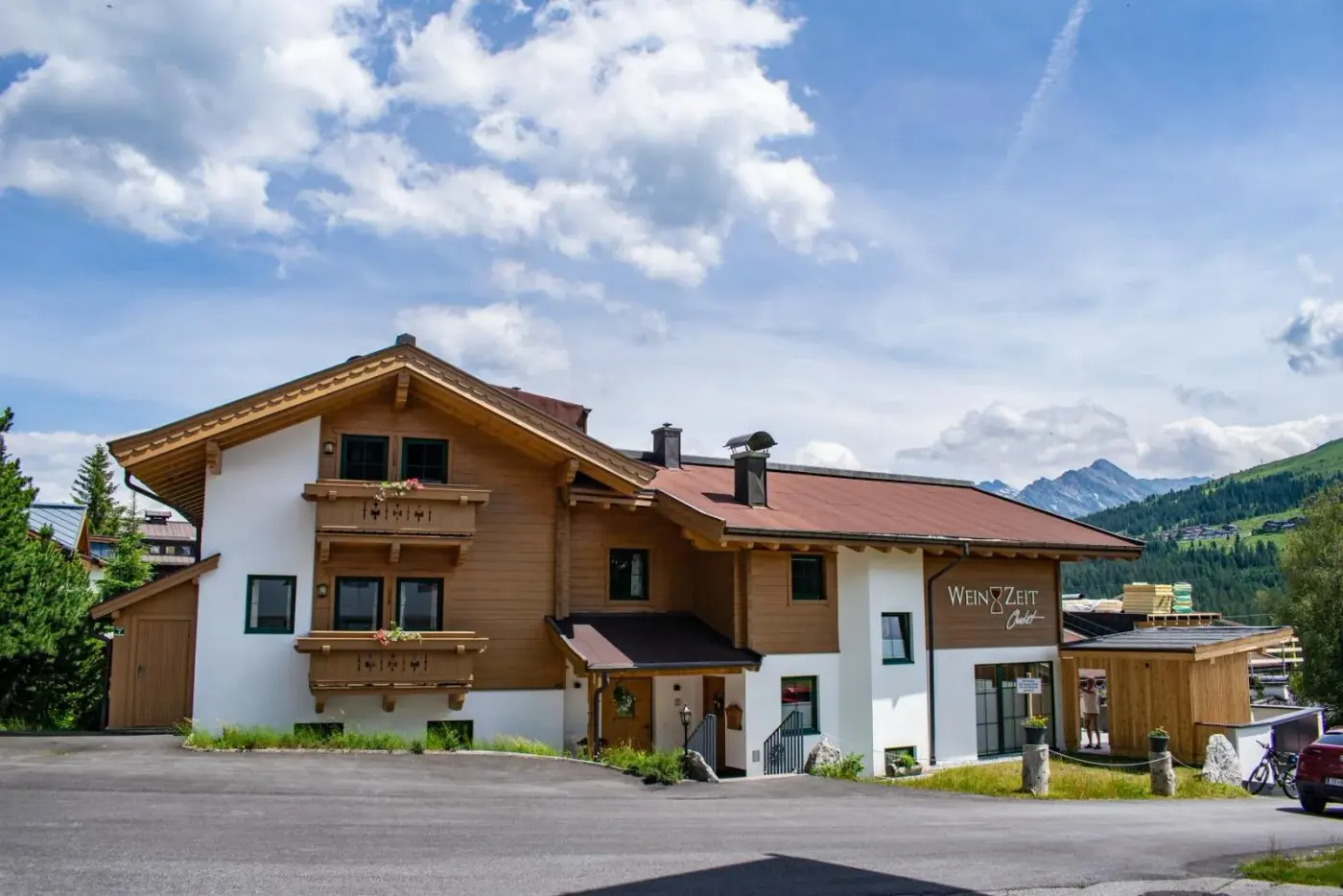 Alpine chalet with timber balconies beneath a blue sky at Weinzeit Chalet in Wald im Pinzgau, Austria.