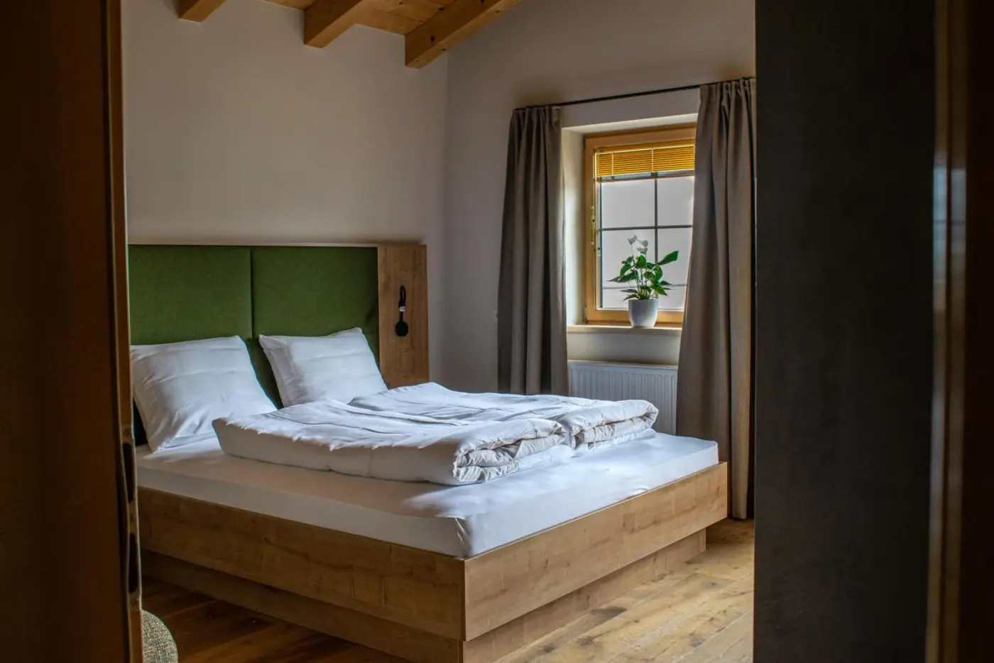 Double bedroom with a timber bed frame and green headboard at Weinzeit Chalet in Wald im Pinzgau, Austria.